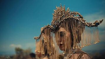 Two women in ornate headpieces with a blurry blue sky background. video