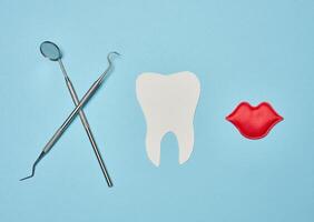 Paper human tooth and dentist medical instruments on blue background photo