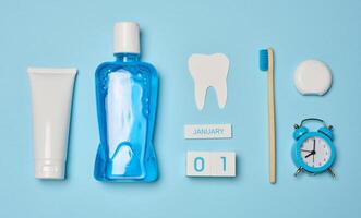Mouthwash, toothpaste tube, dental floss on a blue background, oral hygiene. photo