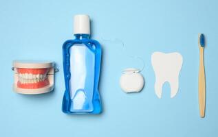 Plastic bottle with mouthwash, wooden toothbrush on blue background photo