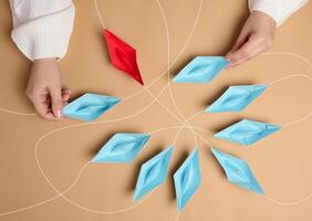 Paper boats with different trajectories in a womans hand on a brown background photo