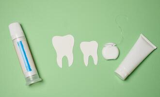 Toothpaste and dental floss on a green background, top view. photo