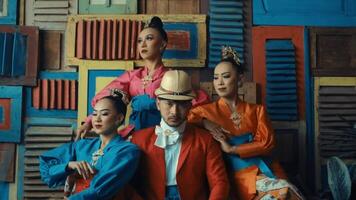 Stylish group in vibrant outfits posing against a colorful abstract background. video