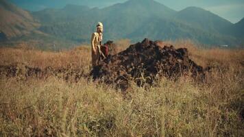 man in traditional attire standing on a hill with scenic mountain backdrop. video