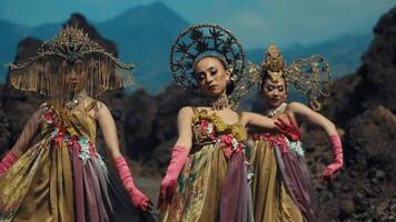 Three women in traditional costumes dancing, with a mountainous backdrop. video