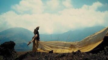 Frau im fließend Kleid mit schier Stoff gegen ein bergig Hintergrund. video