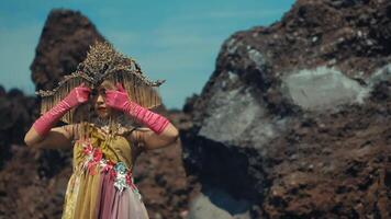 Woman in exotic costume with headpiece posing in rocky landscape. video