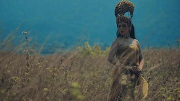 tradicional bailarín en étnico atuendo ejecutando en un natural paisaje con brumoso azul montañas en el antecedentes. video