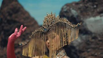 Portrait of a person in traditional attire with an elaborate headpiece against a mountainous backdrop. video