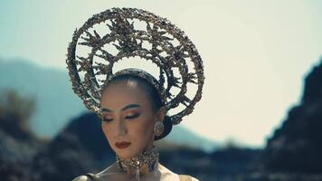 Woman with elaborate headpiece posing in a dramatic outdoor setting. video