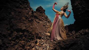 Woman in mythological costume posing between rocks under a dramatic sky. video