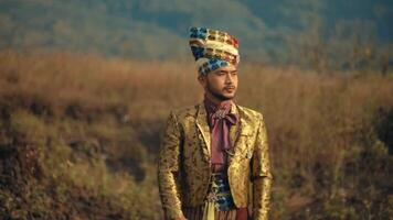 Man in traditional attire standing in a field with a serene expression, cultural fashion concept. video