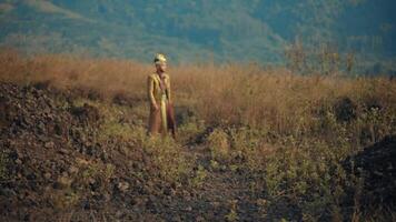 Young man standing in a field at dusk, surrounded by tall grass, evoking a sense of solitude and contemplation. video