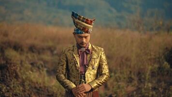 uomo nel tradizionale abbigliamento in piedi nel un' campo con un' riflessivo espressione. video