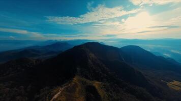 mozzafiato aereo Visualizza di un' lussureggiante verde montagna cresta sotto un' chiaro blu cielo. video