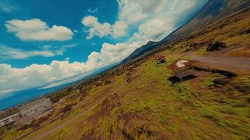 Aerial view of a rugged landscape with a dirt road and a small vehicle under a vast sky with fluffy clouds. video