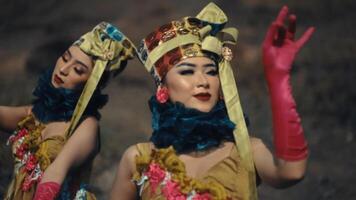 två kvinnor i traditionell asiatisk kostymer med utveckla huvudstycken utför en kulturell dansa. video