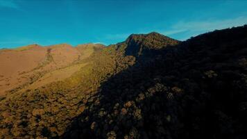 Antenne Aussicht von ein robust Berg Landschaft beim Sonnenuntergang mit Schatten und warm Licht. video