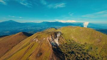 asombroso aéreo ver de un lozano verde montaña cresta debajo un claro azul cielo. video