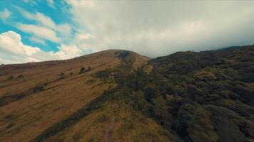 szenisch Aussicht von ein üppig Grün Hang unter ein wolkig Himmel, mit spärlich Vegetation und ein Sinn von Ruhe. video