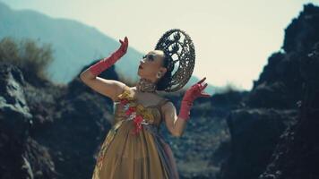 Elegant woman in avant-garde attire posing in a rocky landscape. video