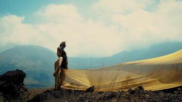 Silhouette of a person holding fabric against a mountainous backdrop with a dramatic sky. video