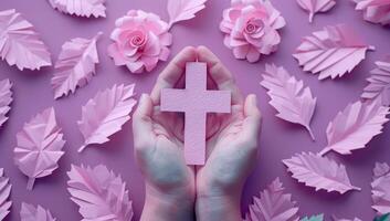 AI generated Female hands holding a pink christian cross surrounded by pink paper flowers. photo