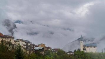 hora lapso de lluvia nubes Moviente terminado pueblo y hermosa montaña de el dolomitas. Tirol. Italia. 4k video