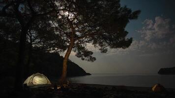 Time lapse of Clouds and the moon move over the bay and tent on the shores of the Mediterranean Sea. Freedom and travel concept. video