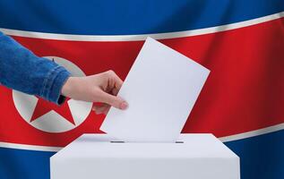 Elections in North Korea. The concept of voting. A hand throws a ballot into the ballot box. The flag of North Korea on the background. photo