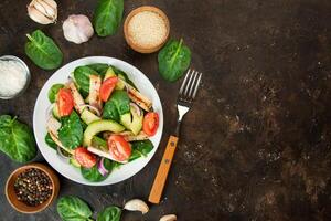 un sano ensalada de pollo mama, Fresco verduras, Espinacas hojas, aguacate y Tomates en un oscuro antecedentes. ensalada de verduras con carne. el concepto de dieta alimento. Copiar espacio. benner alimento. foto