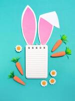 Easter composition. Notepad with place for text with rabbit ears on a green background. Flat lay, top view, copy space. photo