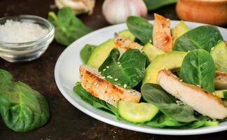 Grilled chicken breast with avocado and herbs on a dark background. Dietary nutrition. Healthy lifestyle. Side view. Close-up. photo