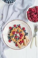 Waffles with fresh raspberries, blueberries for breakfast. Belgian waffles. Light wooden background. photo