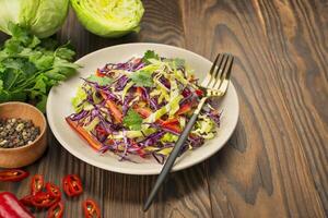 brillante ensalada de púrpura repollo, blanco repollo, campana pimienta en un plato en un de madera mesa. Fresco vegetal ensalada. comida antecedentes. vegetariano plato. ver desde arriba. Copiar espacio. foto