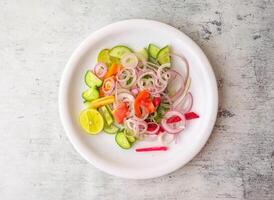 Fresh salad with onion, cucumber, carrot, lemon and tomato served in a plate isolated on background top view of indian and pakistani desi food photo