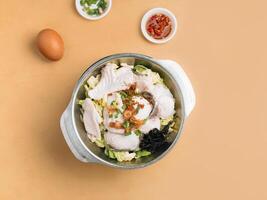 Sliced Fish Xiao Wan in a bowl with soup, chili sauce and spring onion top view on wooden table photo