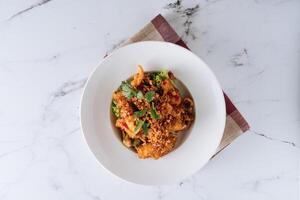 Indonesian food Salt and Chilli Squid in a dish isolated on mat top view on grey marble background photo