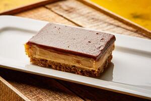 Chocolate Caramel Slice bar served in dish isolated on wooden table top view of arabic sweet dessert photo