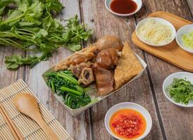 Cerdo nudillo arroz bento con chile salsa, fideos, cuchara y palillos servido en plato aislado en servilleta parte superior ver de hong kong comida foto