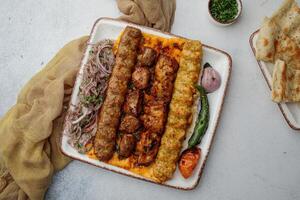 Spicy Mix grill platter with chicken tikka boti kabab, beef shish kebab and onion served in dish isolated on table top view of arabian food photo