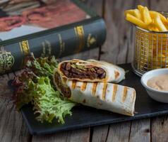 beef shawarma with fries isolated on cutting board side view of fastfood on wooden background photo