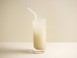 A glass of barley water with straw isolated on grey background side view photo