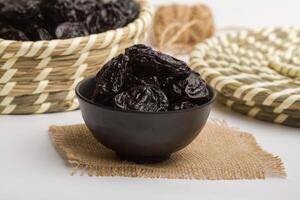 dry prunes served in bowl isolated on napkin side view of dry fruits on grey background photo