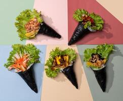 Assorted japanese wraps Spicy TAMAGO, CALIFORNIA wrap, POKE SALMON Skin, SPICY TUNA roll topping with salad leaves isolated on sky blue background top view fast food photo