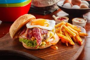 Bacon cheese burger with fries served in a dish isolated on wooden background side view photo