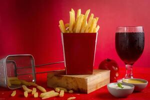 Hot potato fries isolated on wooden board with mayo dip and cold drink side view photo