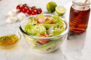 Healthy AVOCADO SALAD with tomato, lemon and honey served in a dish isolated on grey background side view photo