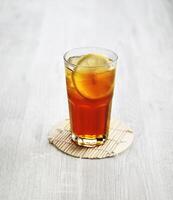 A glass of fresh iced Lemon Tea with lemon slice isolated on grey background side view photo