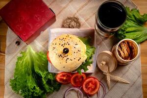 Traditional Beef burger with cold drink, tomato slice isolated on wooden board top view on table fast food photo